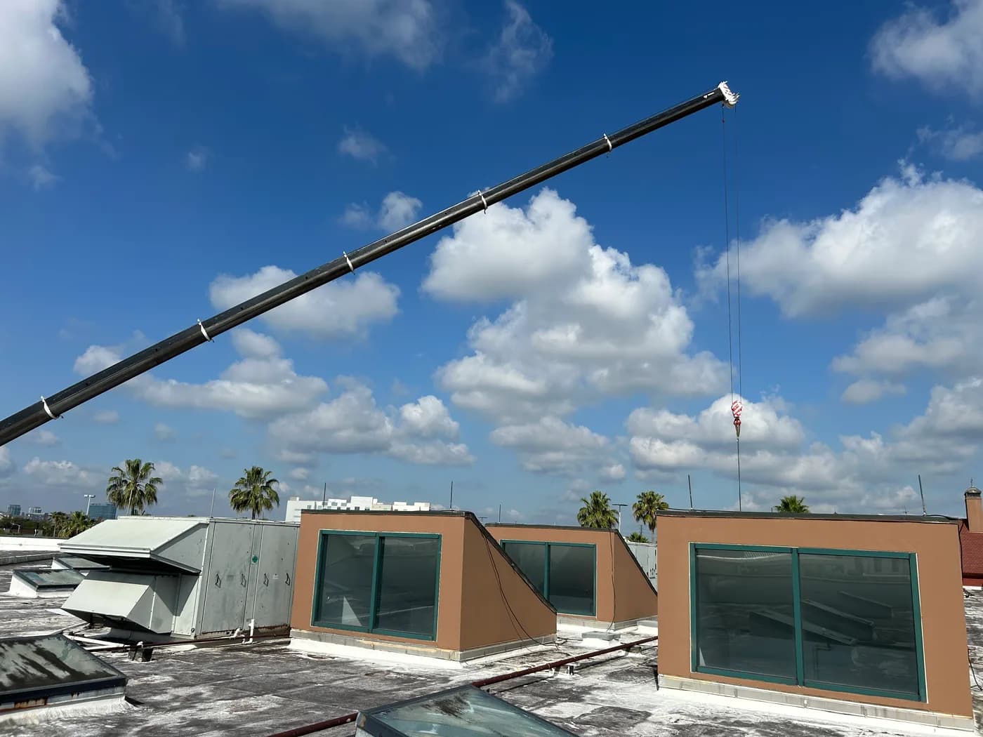 Crane lowering commercial rooftop HVAC equipment onto a Florida building