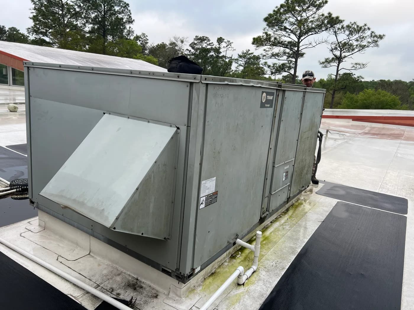 Blue Works technician servicing a commercial Trane Voyager rooftop unit on a Florida flat roof